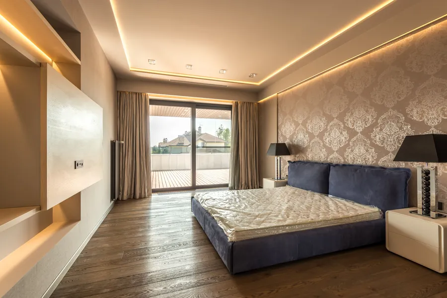 Bedroom with a layered ceiling and warm cove lighting